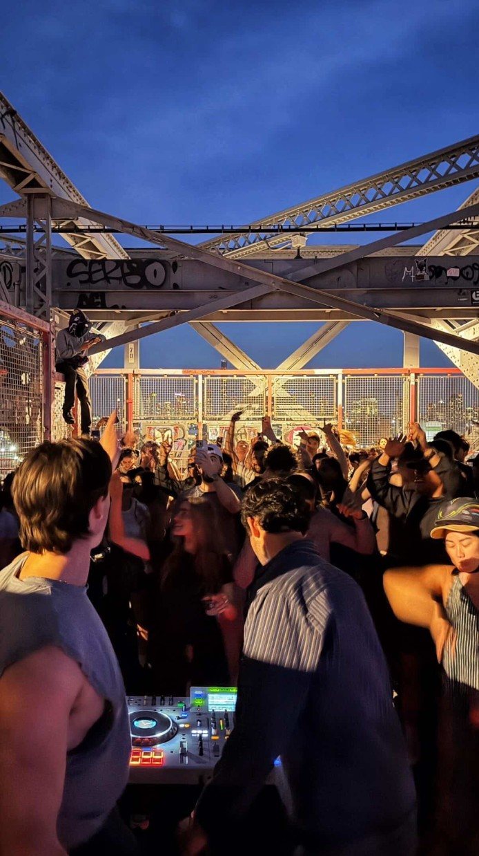 Crowd dancing on the Williamsburg Bridge at dusk